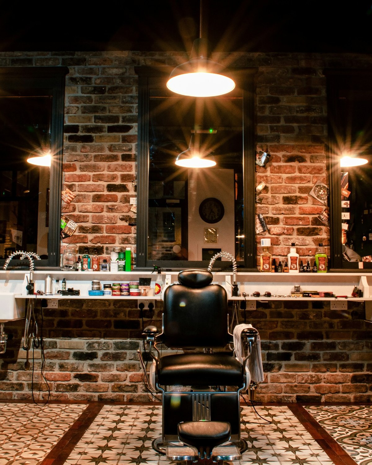 The row of barber's chairs and the mirrors along the brick wall, under the shop's pendant lamps