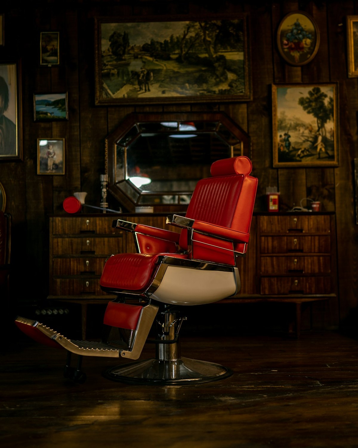 The red chair in the back room, the wall behind it hung with framed pictures